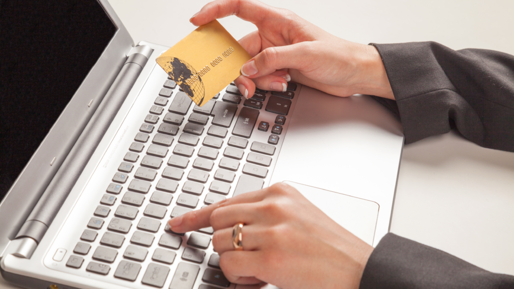 Woman holding gold credit card typing on laptop. Portrays as spending money online.